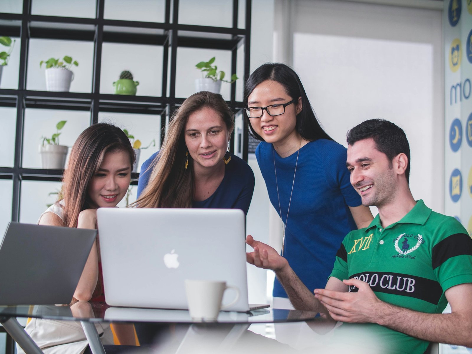 Stock photograph of colleagues discussing work together around a laptop